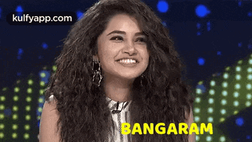 a woman with long curly hair is smiling with the words bangaram written on her face .