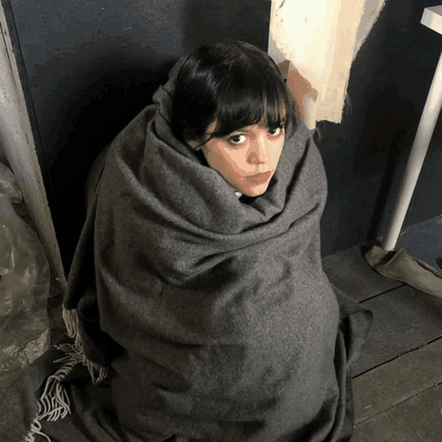 a woman is wrapped in a gray blanket
