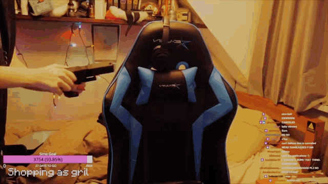 a person is holding a gun in front of a blue and black chair