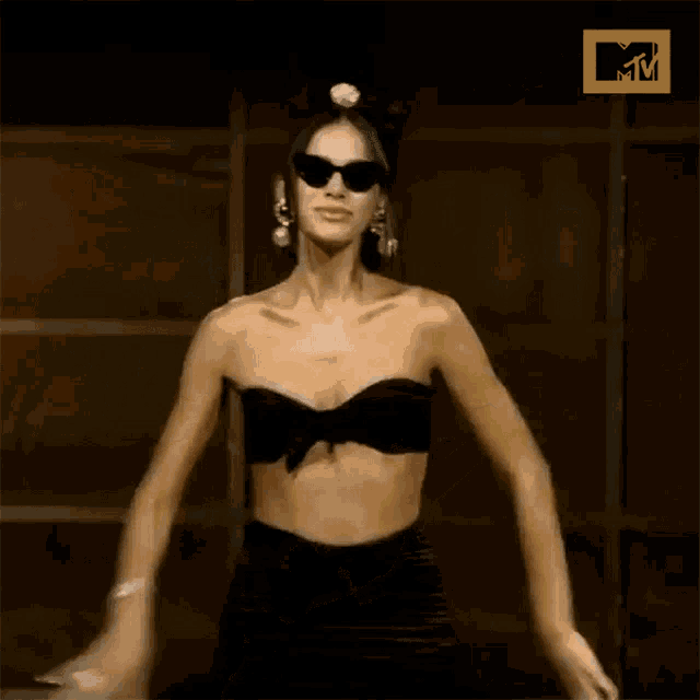a woman wearing sunglasses and earrings is dancing in front of a mtv logo .