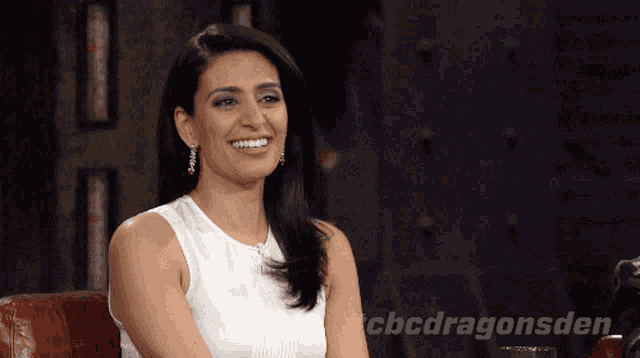a woman is smiling in front of a sign that says cbcdragonsden on it