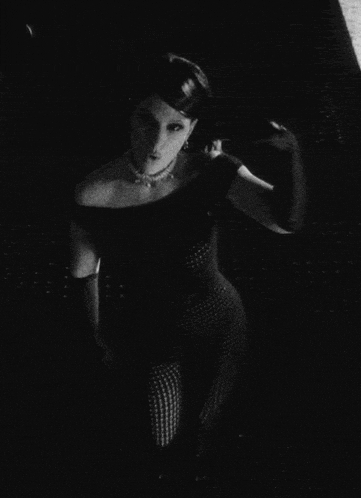 a black and white photo of a woman in a black top and gloves