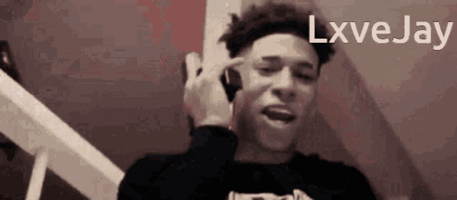 a young man is talking on a cell phone with the name lxvejay written above him .