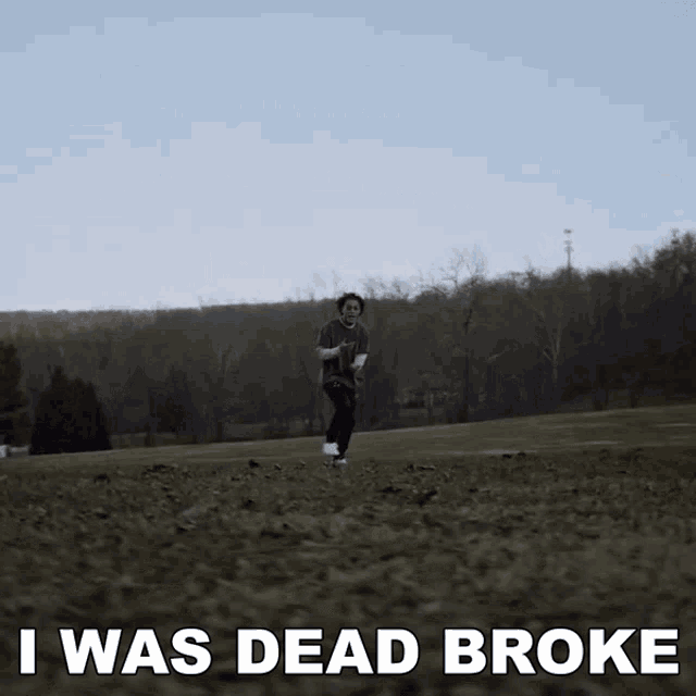a man running in a field with the words " i was dead broke " behind him