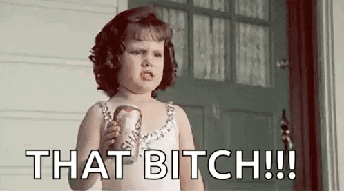 a little girl is holding a can of soda and making a funny face .