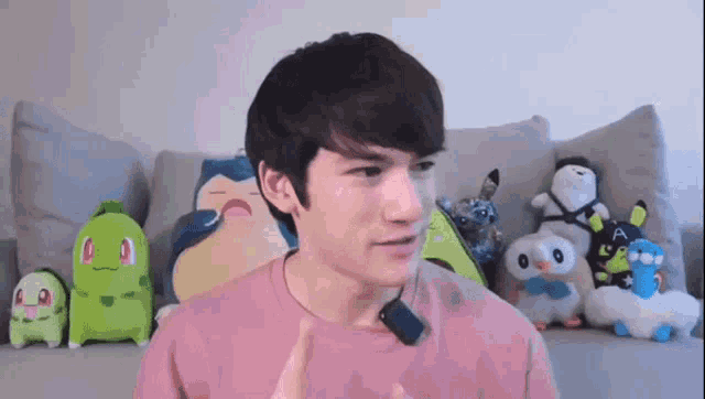a man wearing a pink shirt is standing in front of stuffed animals