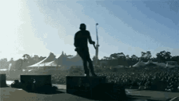 a man playing a guitar on a stage in front of a crowd