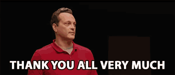 a man in a red shirt is giving a speech and saying thank you all very much .
