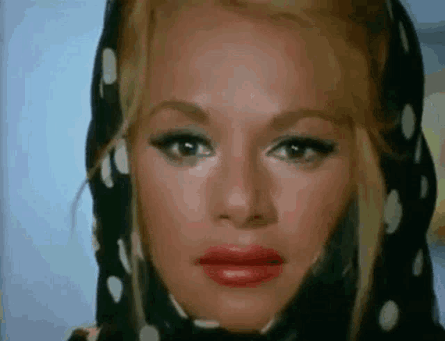 a close up of a woman 's face with a scarf around her head and red lipstick .