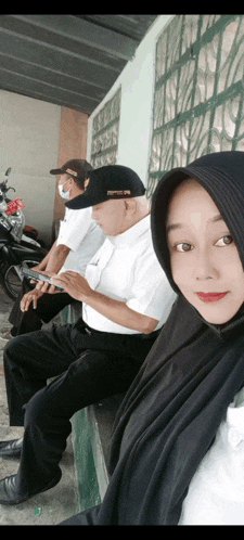 a woman wearing a hijab sits next to a man wearing a hat that says ' sdp ' on it