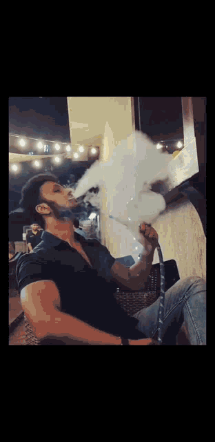 a man is smoking a hookah and blowing smoke out of it