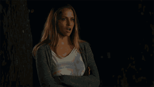 a woman with her arms crossed is wearing a gray cardigan