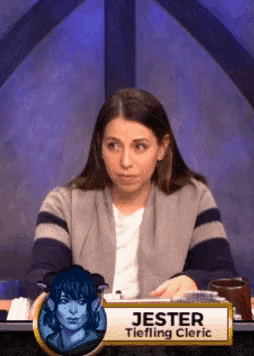 a woman sitting at a table with a sign that says jester tiefling cleric on it