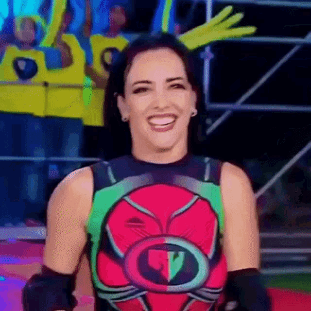 a woman in a superhero costume is smiling while standing in front of a crowd .