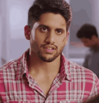 a man with a beard is wearing a pink plaid shirt and looking at the camera .
