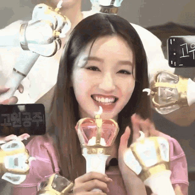 a woman is smiling while holding a light stick with a crown on top of it .