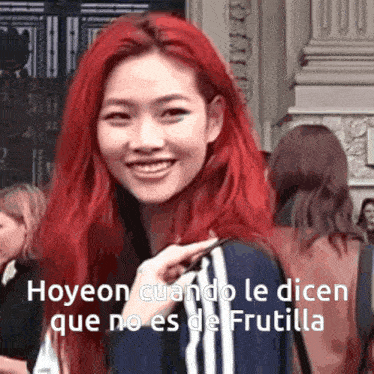 a woman with red hair is smiling and talking in spanish