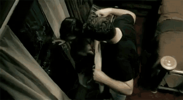 a man and a woman are kissing in front of a window while holding a baby .
