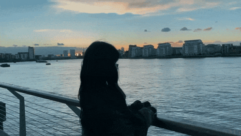 a woman looking out over a body of water with buildings in the background