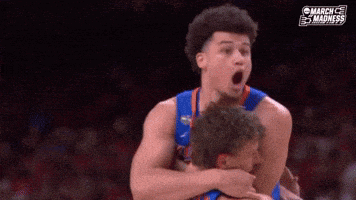 a basketball player is hugging another player with his mouth open during a game .