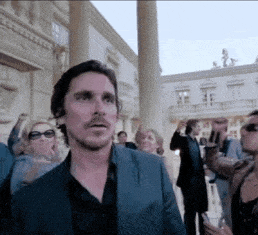 a man in a suit stands in front of a crowd