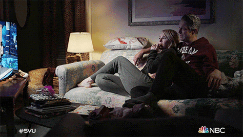 a man and a woman are sitting on a couch with the nbc logo on the bottom