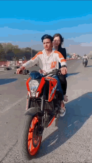 a man and a woman are riding a motorcycle on a road .