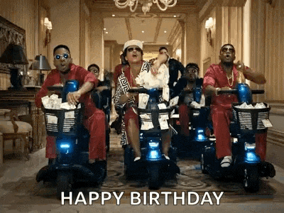 a group of men are riding scooters in a hallway with a happy birthday message .