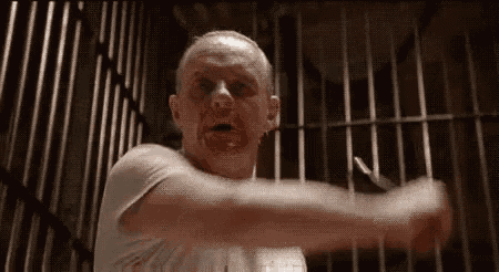 a man with blood on his face is standing in front of a prison cell .