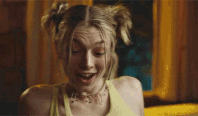 a woman with pigtails is smiling and wearing a necklace