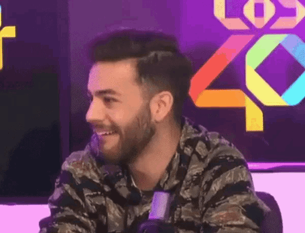 a man with a beard is smiling in front of a los 40 logo