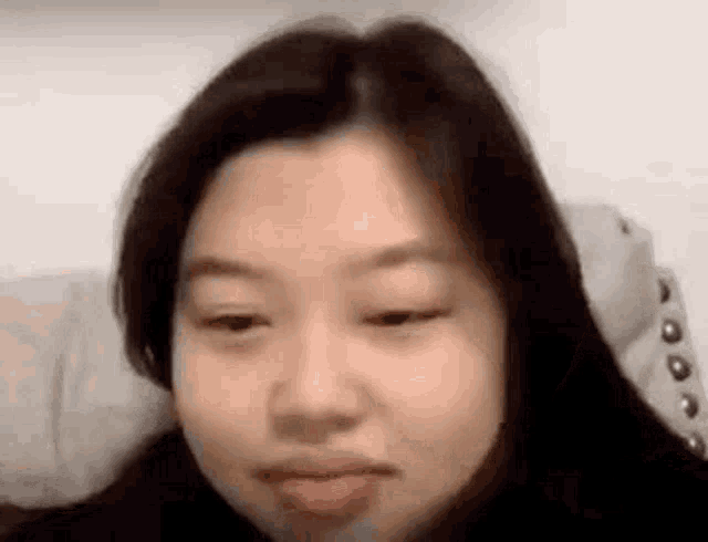 a close up of a woman making a funny face while sitting on a bed .