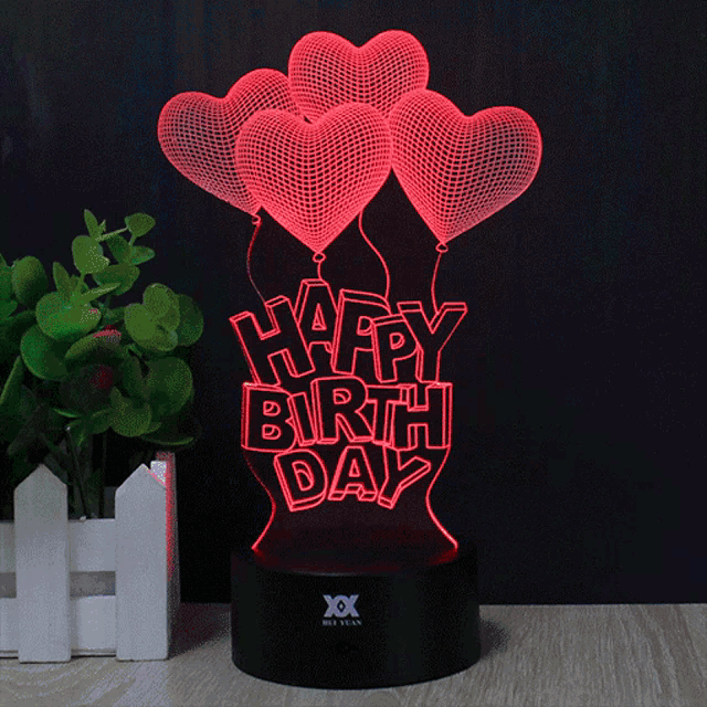 a light that says happy birthday with balloons in the background
