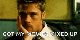 a man in a suit and tie is sitting down with his hand on his chin and the words `` got my movies mixed up '' .