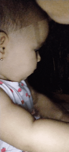 a baby with ear piercings looks down at something