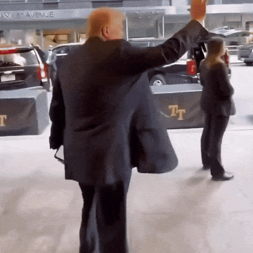 a man in a suit is standing in front of a building that says t on it