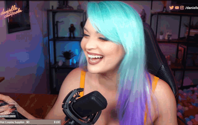 a woman with blue hair is laughing in front of a microphone