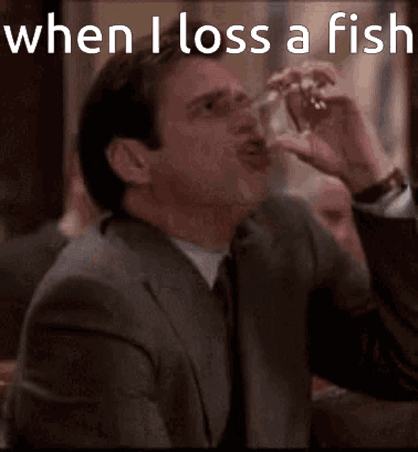 a man in a suit and tie is drinking from a glass with the words when i lose a fish above him .