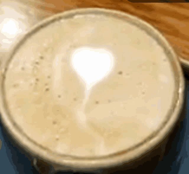 a close up of a cup of coffee with a heart shaped latte art on the top .