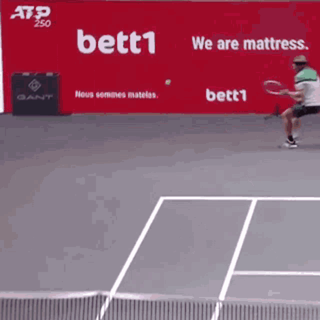 a tennis player is swinging a racket on a court in front of an ad for bett1