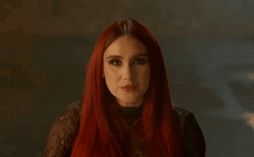 a woman with red hair is pointing her finger at the camera .