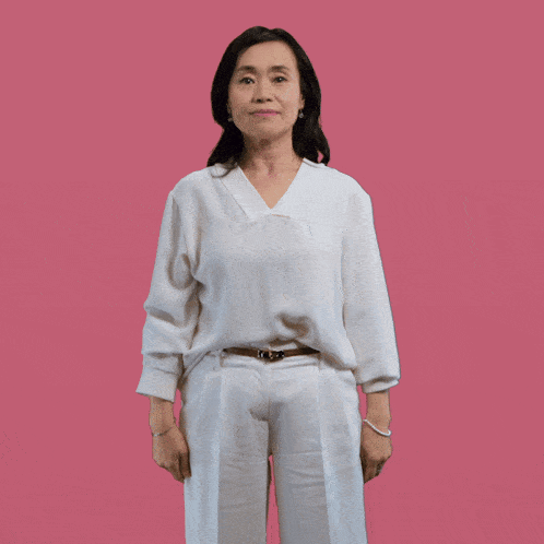 a woman in a white shirt and white pants is standing with her hands outstretched