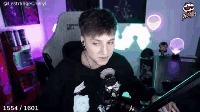 a young man is sitting in front of a microphone with a pringles can in his hand