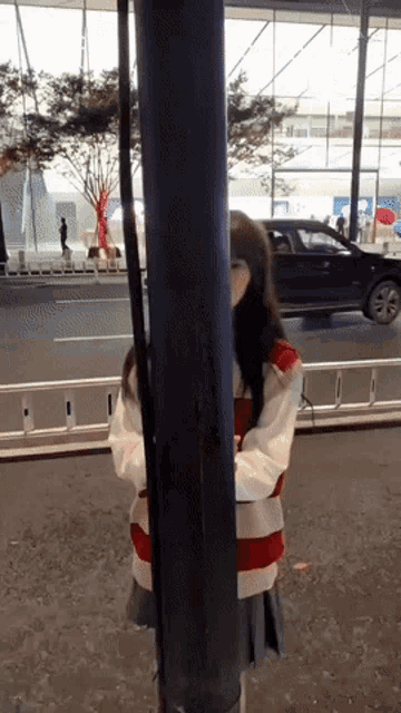 a woman in a red and white striped sweater is standing in front of a pole