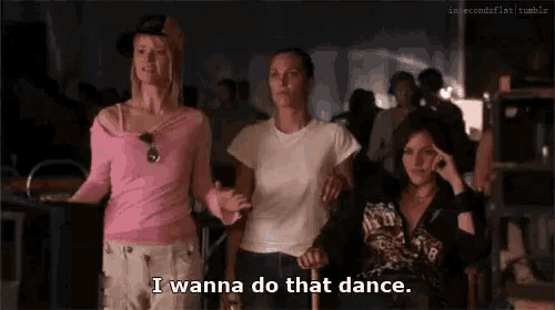 three women are standing in a room and one of them is saying i wanna do that dance