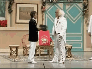 a man in a white suit is holding a red bag that says christmas