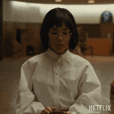a woman wearing glasses and a white shirt with a netflix logo on the bottom