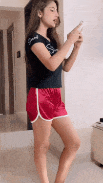 a woman wearing red shorts and a black shirt with the word summer on it