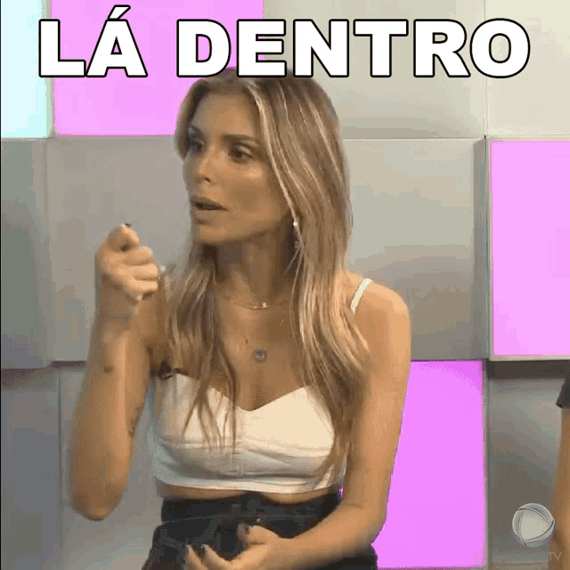 a woman in a white crop top is pointing at something with the words la dentro behind her