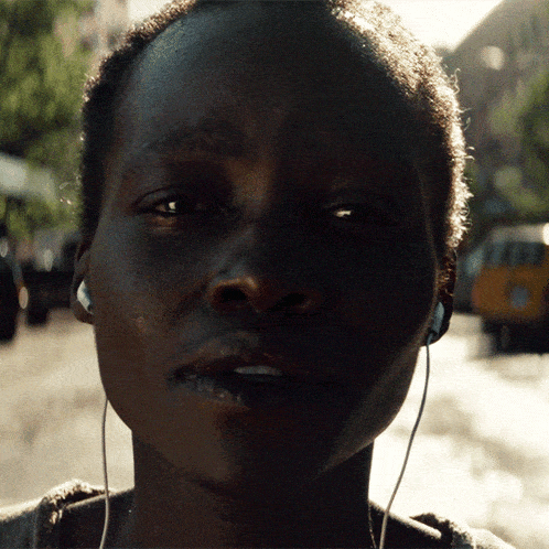 a woman wearing headphones looks at the camera